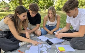 Nastolatkowie rozwiązują wspólnie łamigłówki matematyczne na świeżym powietrzu