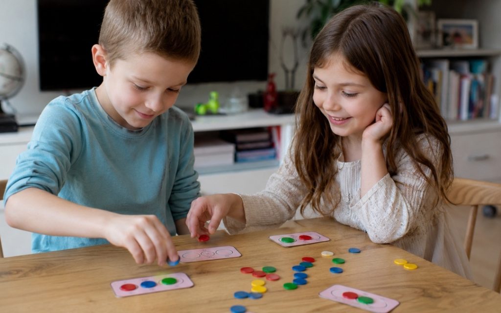 Dwoje dzieci gra w grę edukacyjną ucząc się dzielenia.