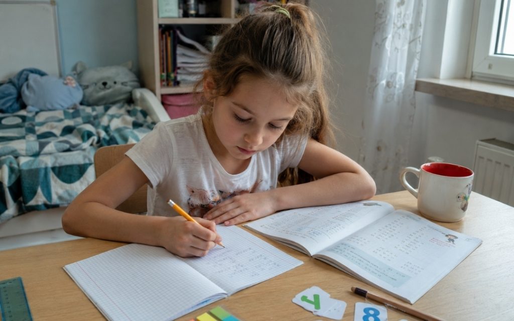 Dziecko uczy się matematyki w przytulnym pokoju przy biurku.