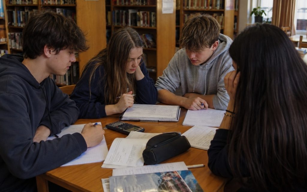Grupa licealistów wspólnie planuje powtórkę do sprawdzianu z matematyki w bibliotece.