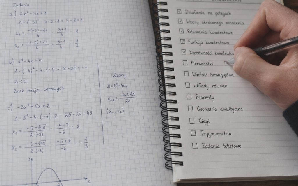 Zbliżenie na checklistę tematów do sprawdzianu z matematyki obok zeszytu z rozwiązanymi zadaniami.