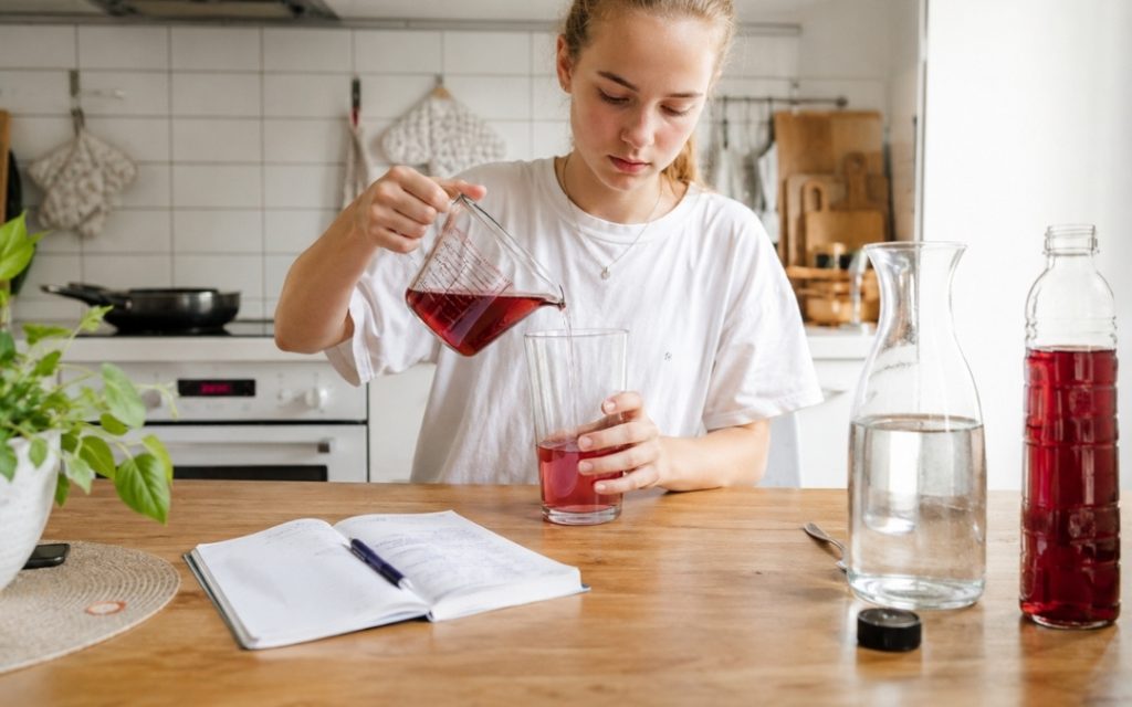 Licealistka pracuje przy stole w kuchni, ucząc się matematyki i licząc proporcje w codziennym otoczeniu.