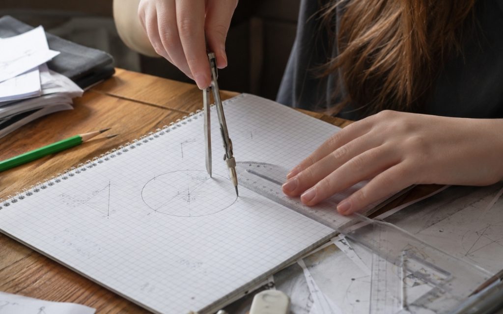 Zbliżenie na notatnik z rysunkami matematycznymi, figurami geometrycznymi i starannymi szkicami wykonanymi podczas nauki.