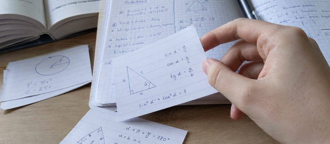 Zbliżenie na fiszkę matematyczną z rysunkiem trójkąta, wzorami trygonometrycznymi i notatkami w zeszycie.